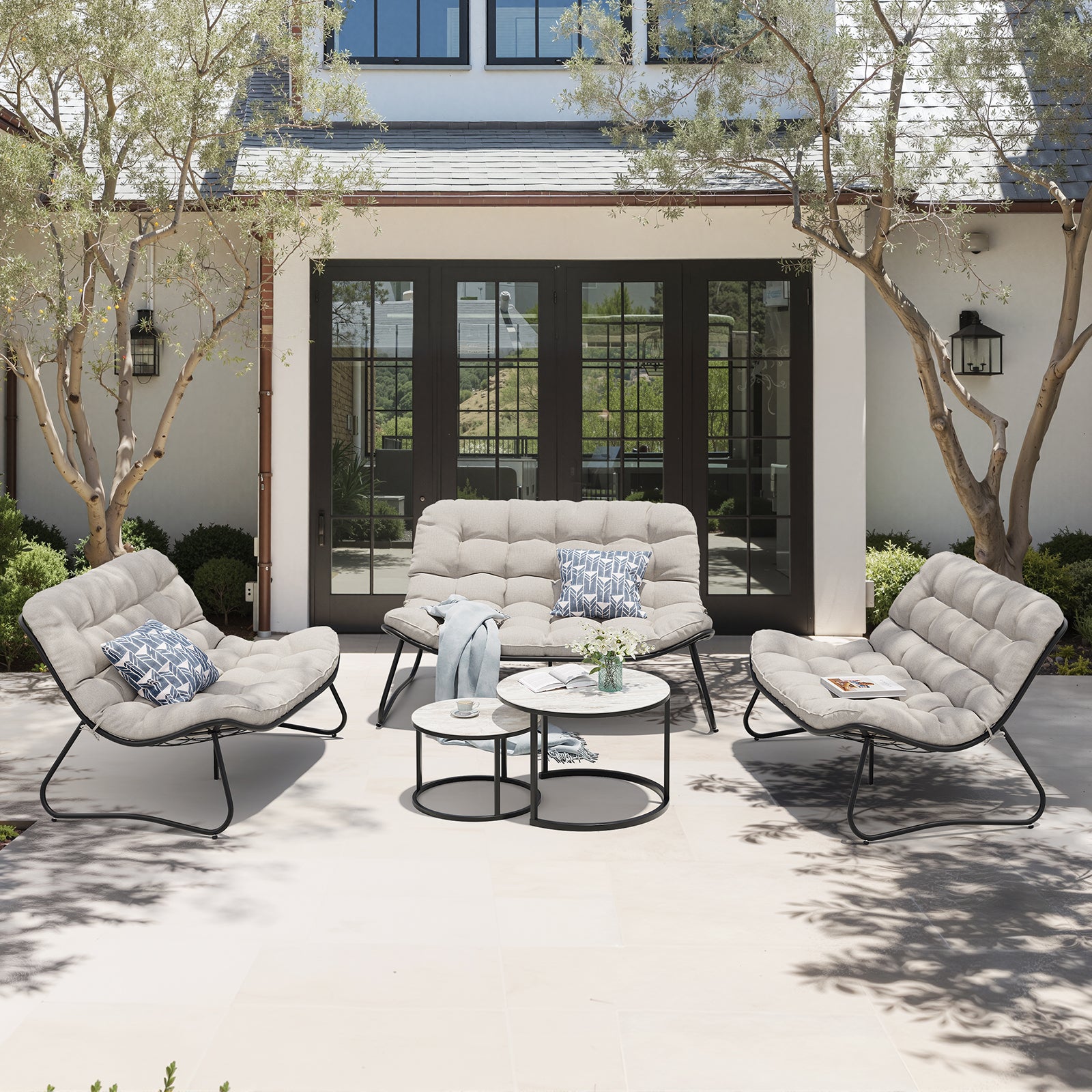 Steel outdoor loveseat and chairs set with side tables in a backyard setting