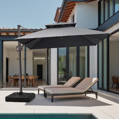 A charcoal grey 10x10 ft square cantilever patio umbrella with heavy-duty base shading chaise lounge chairs at a modern villa poolside
