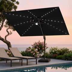 Tilted 12x9 ft black lighted cantilever umbrella with heavy-duty base shading poolside lounge chairs at sunset