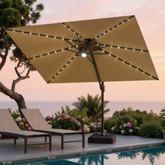 Tilted 12x9 ft beige lighted cantilever umbrella with wheeled base shading poolside lounge chairs at sunset