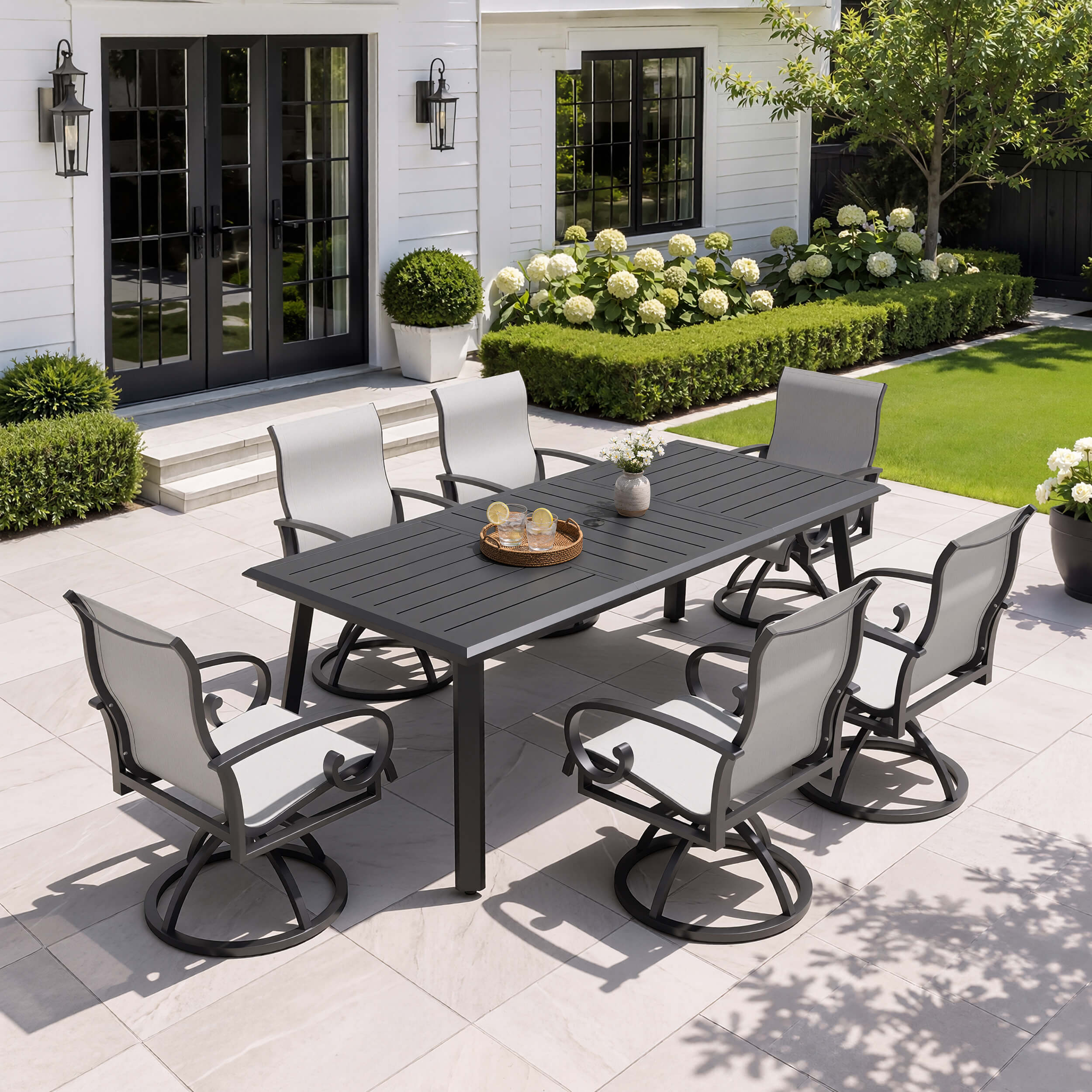 7-piece patio dining set with aluminum expandable table and 6 grey swivel Sunbrella chairs on patio.