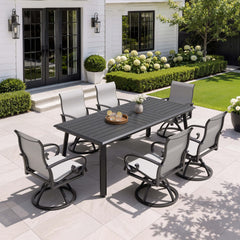 7-piece patio dining set with aluminum expandable table and 6 grey swivel Sunbrella chairs on patio.