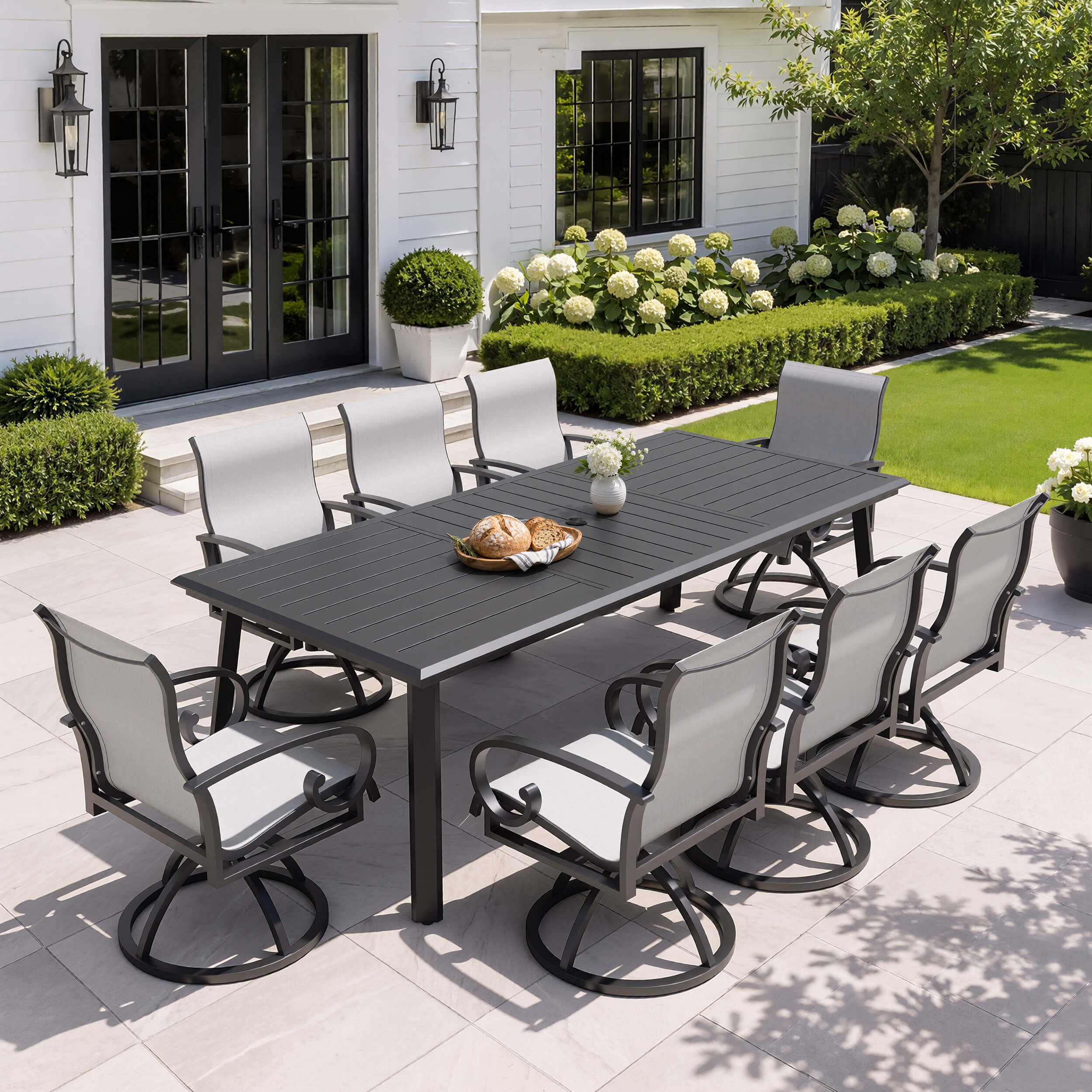9-piece patio dining set with aluminum expandable table and 8 grey swivel Sunbrella chairs on patio.