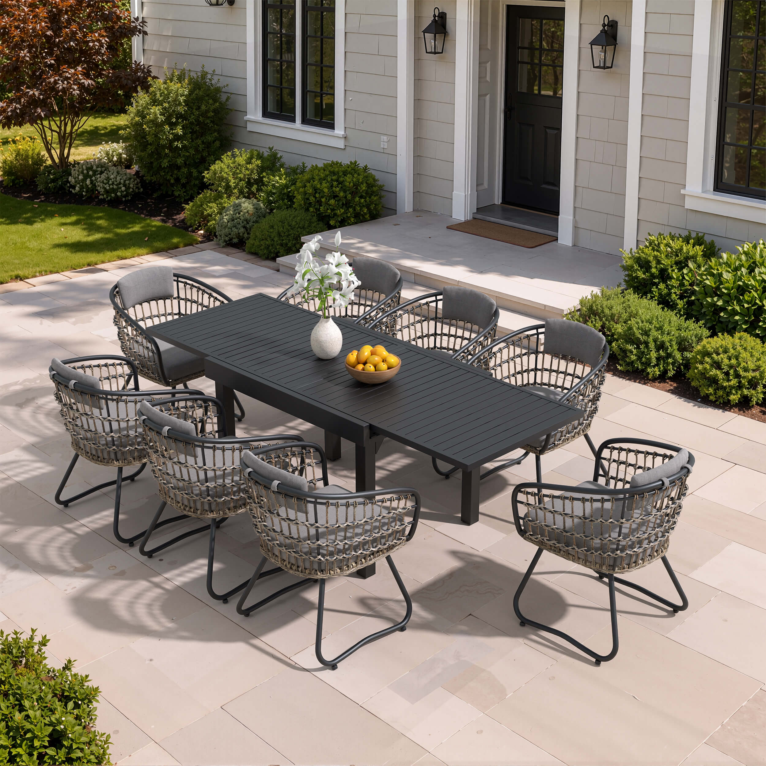 9-piece expandable patio dining set with black aluminum table and 8 grey PE rattan chairs on patio.